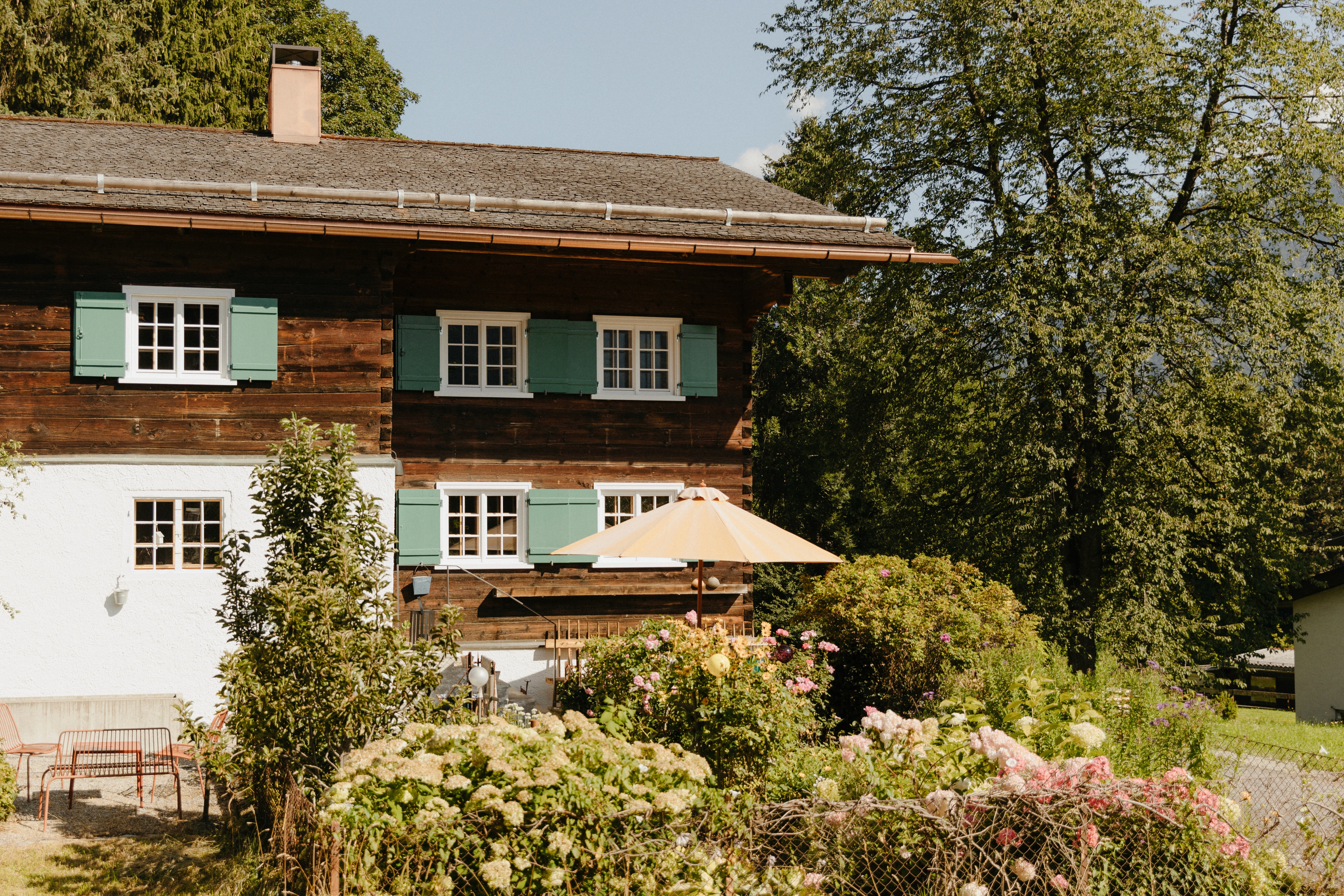 The garden in fron of Benedikta featuring bushes, flowers and trees.