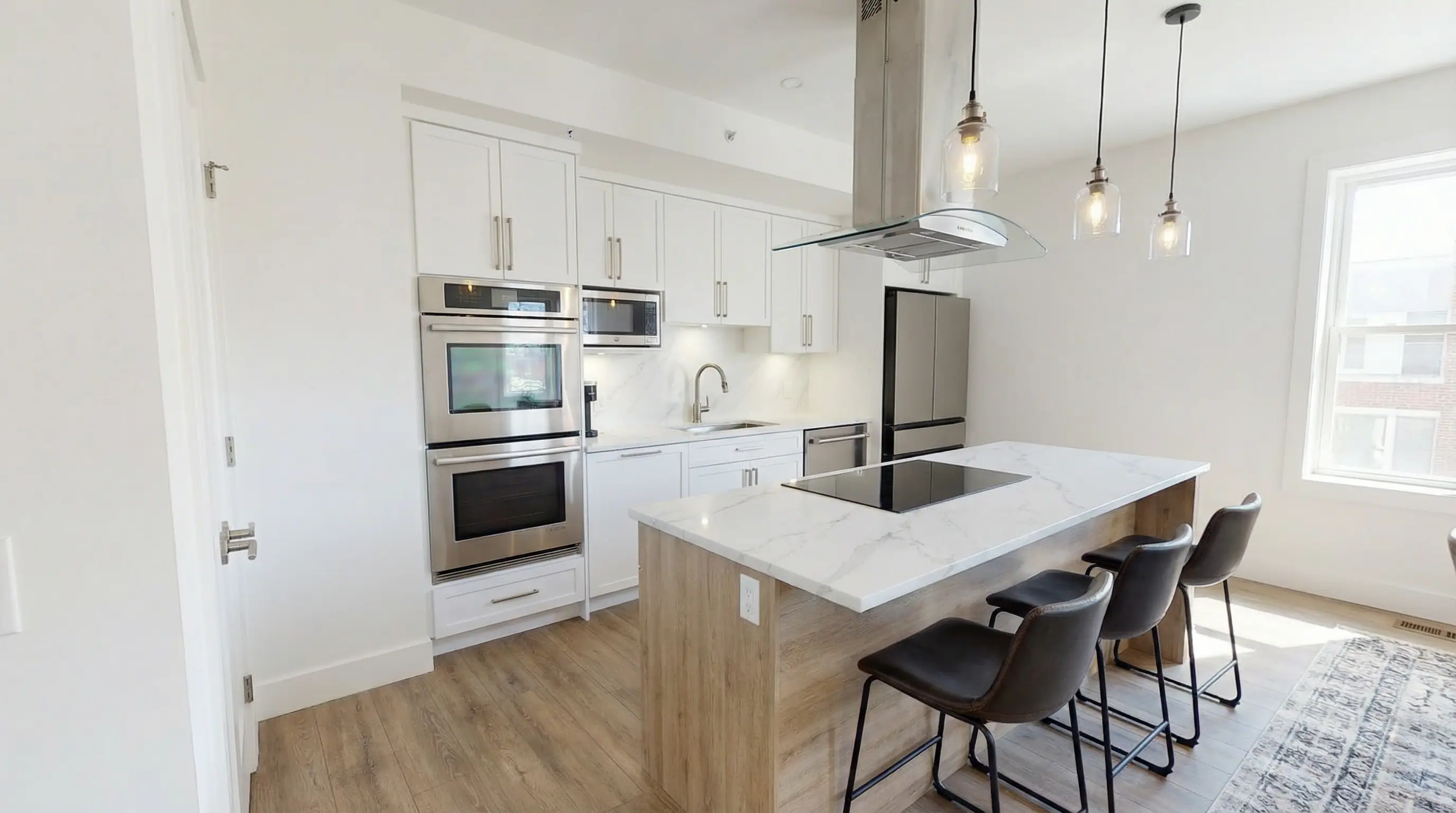 Custom-designed kitchen with quartz marble island, double wall oven, stainless steel appliances, and glass pendant lights in Vancouver Custom Homes' West 16th Vancouver multiplex