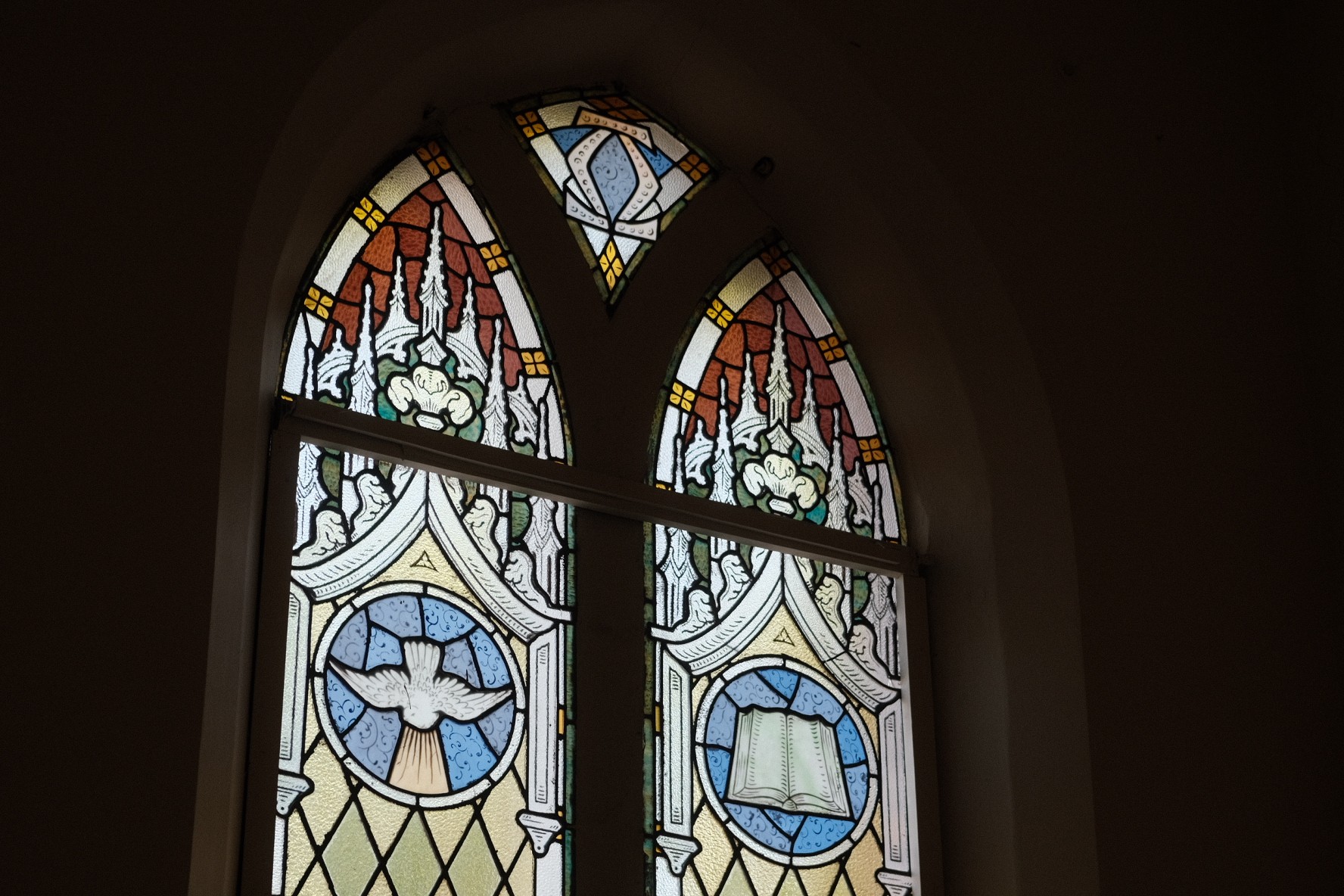 A restaurant interior featuring marble countertops, brown leather chairs, wood-paneled walls, and round pendant lights hanging above a bar set with wine glasses.