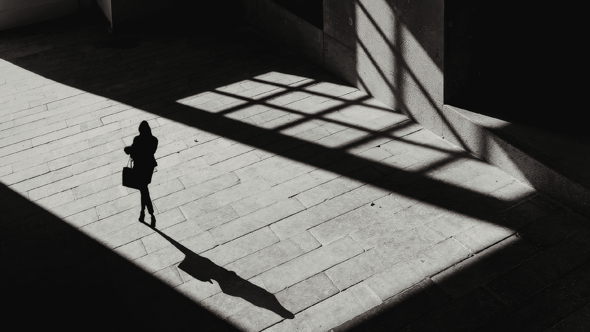 A winding road cuts through rocky terrain, surrounded by patches of green grass and illuminated by sunlight.