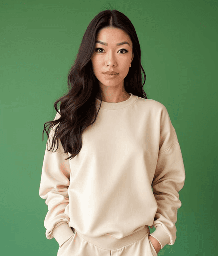 A smiling man with glasses, curly hair, wearing a maroon hoodie, poses against a dark background.