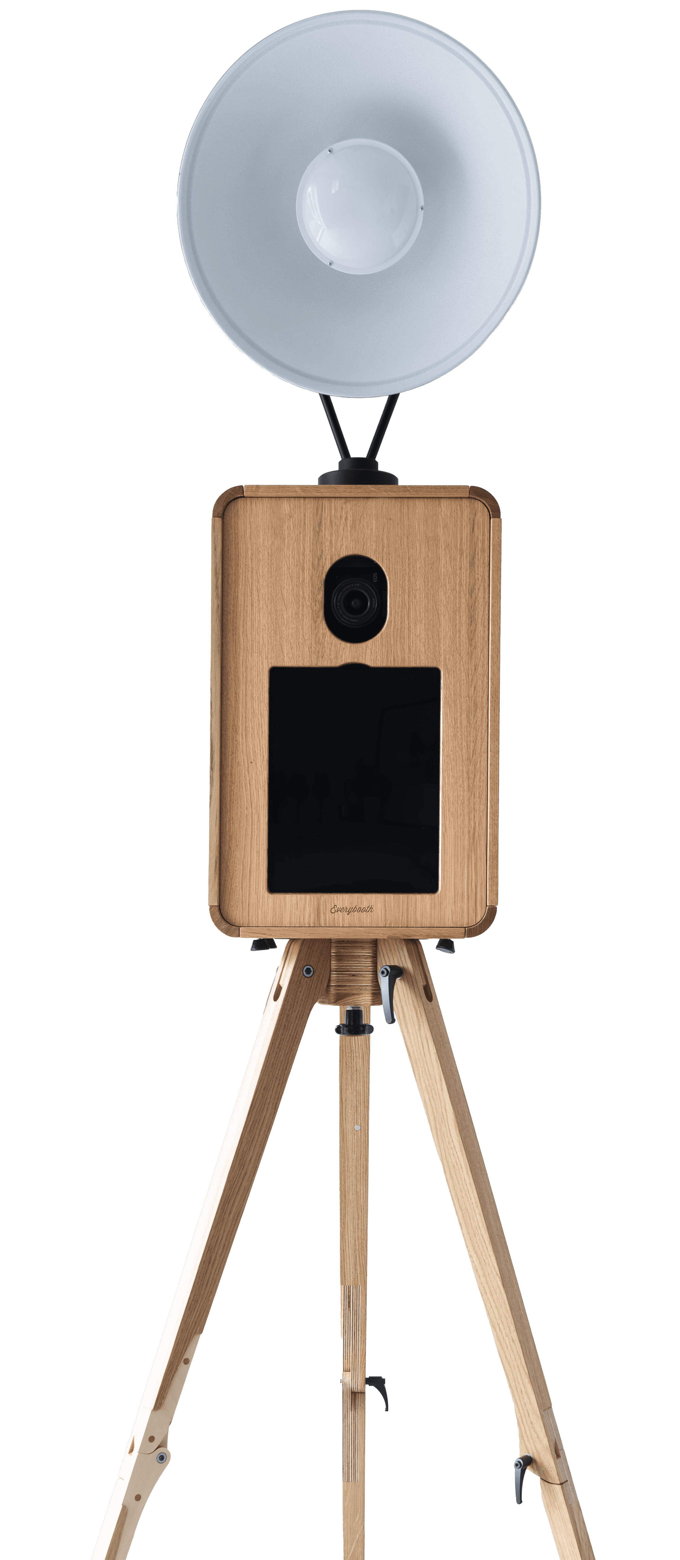 A wooden retro style photo booth with three legs, a large touch screeen, camera hole, and a large light lamp attached at the top.