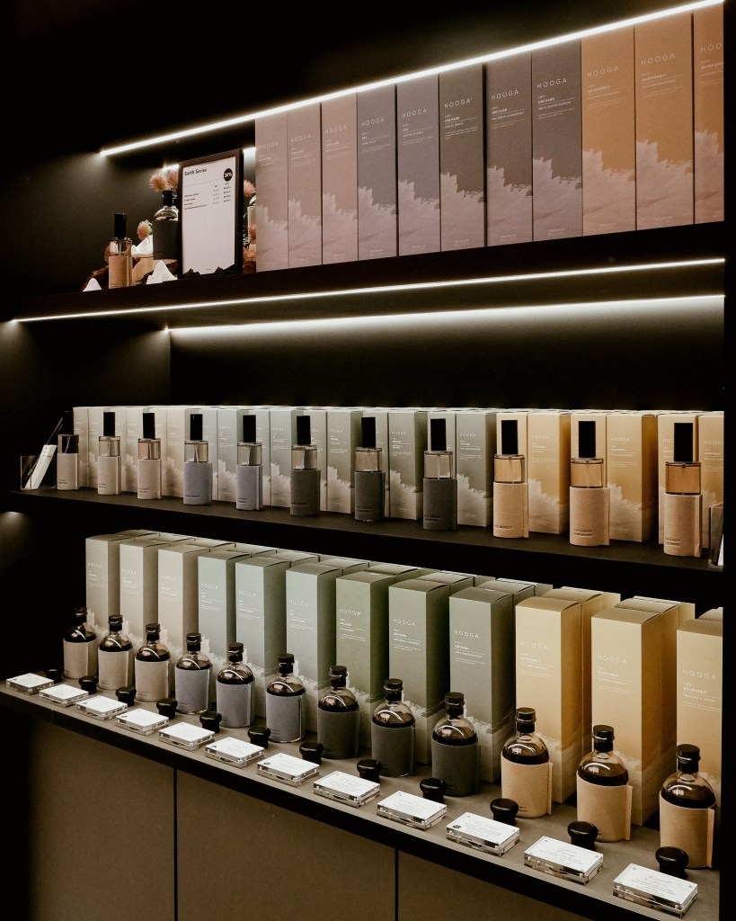 A neatly organized display of various home fragrance products, featuring elegant packaging in muted colors, highlighting the HOOGA brand in a softly lit retail environment.