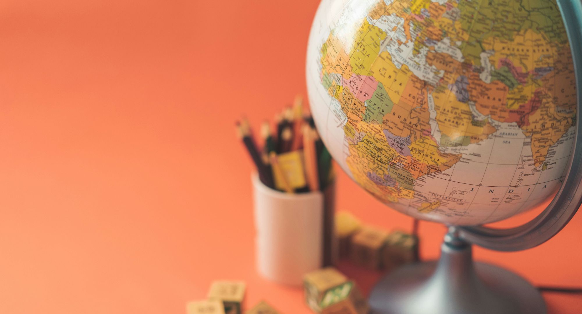 globo e lapís num porta-lapís em um fundo laranja