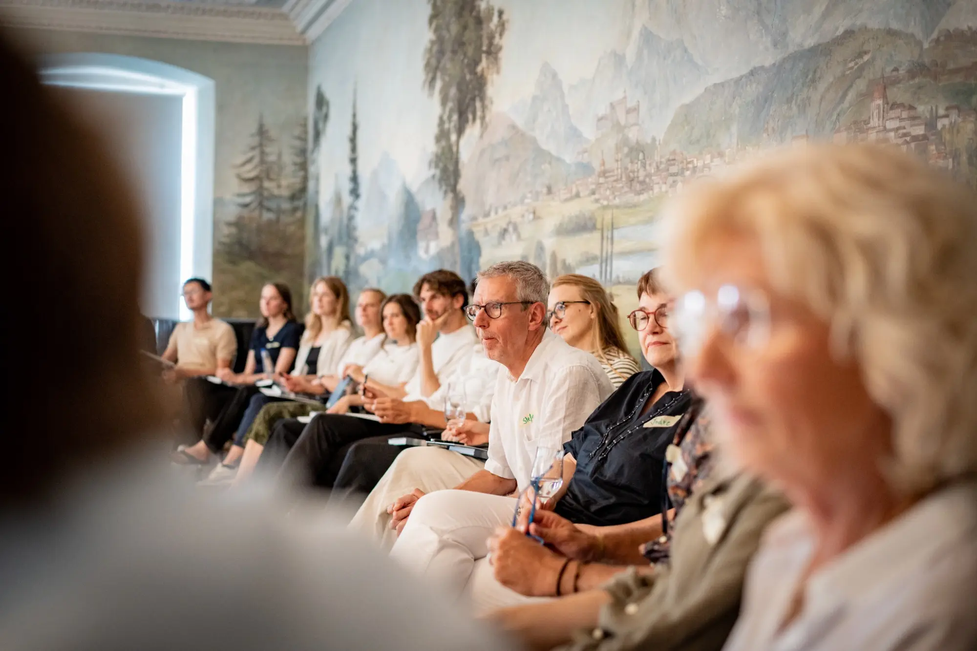 Teilnehmende hören bei einem gemeinsamen Workshop aufmerksam zu