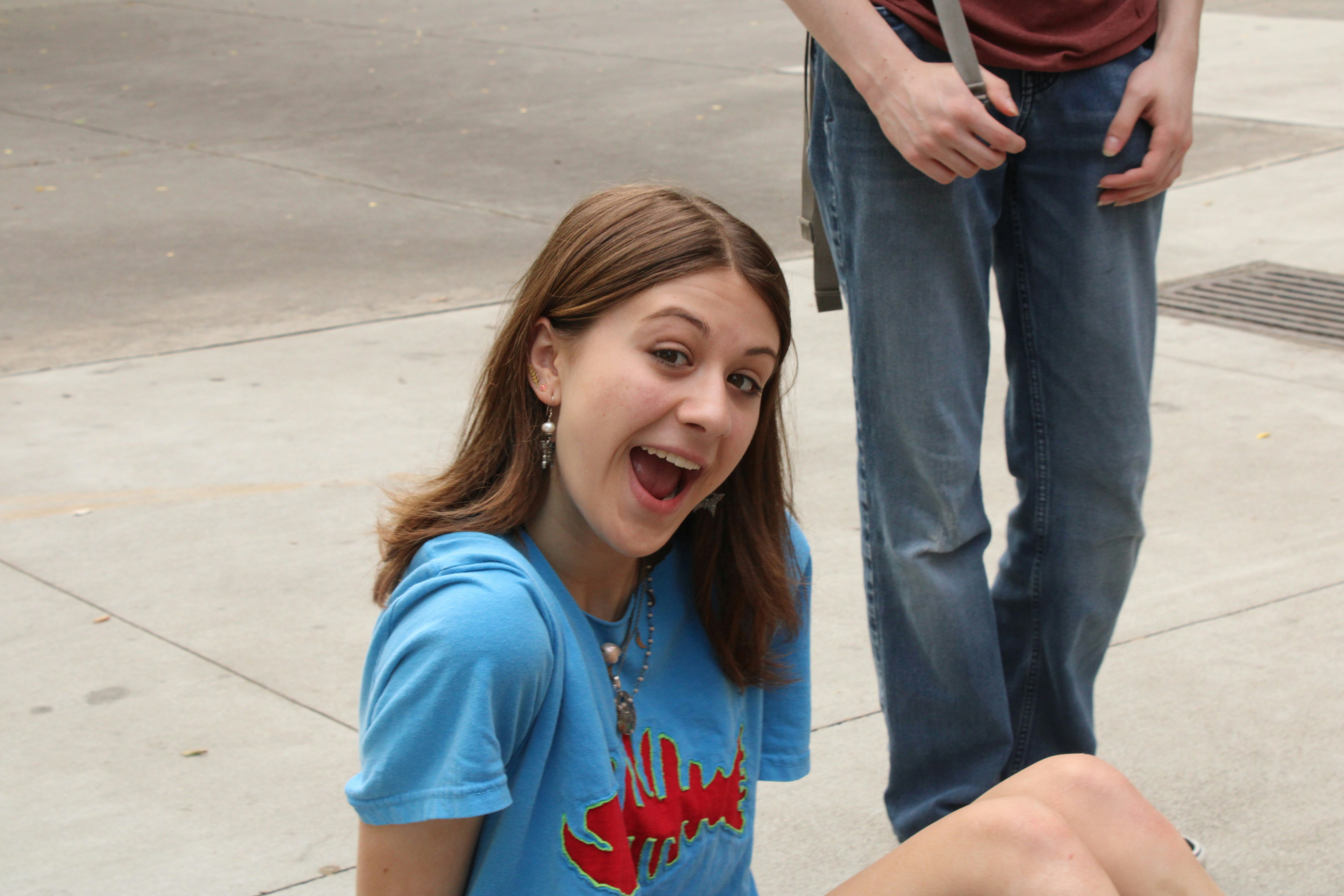 a girl sitting on the ground with a toothbrush in her mouth