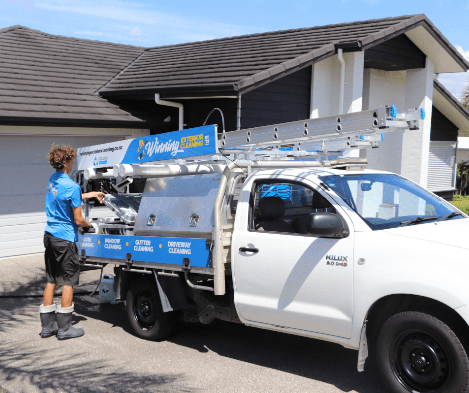 Asher and team preparing house washing equipment beside service truck parked in residential Auckland driveway