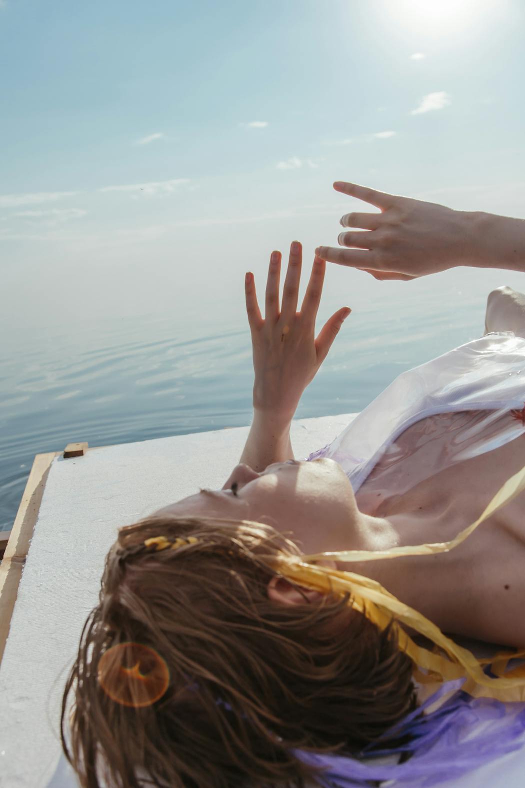 A woman sunbathing on wooden platform near the sea