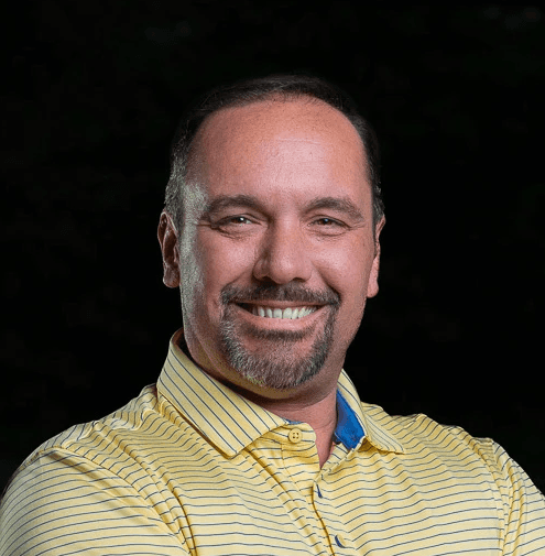 Man wearing a beanie and shirt works on a laptop.