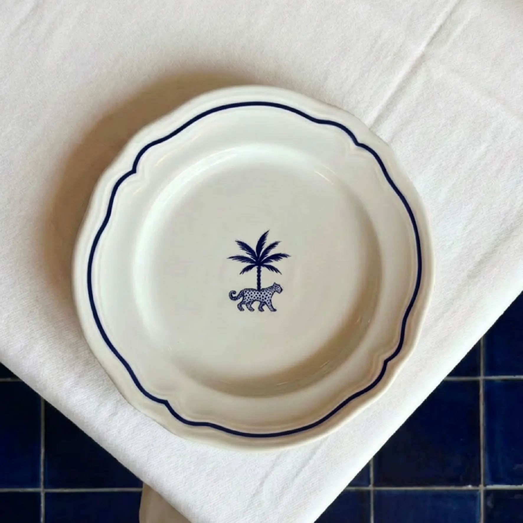 A white plate with dark blue trimming and the palm leopard logo mark printed in the middle