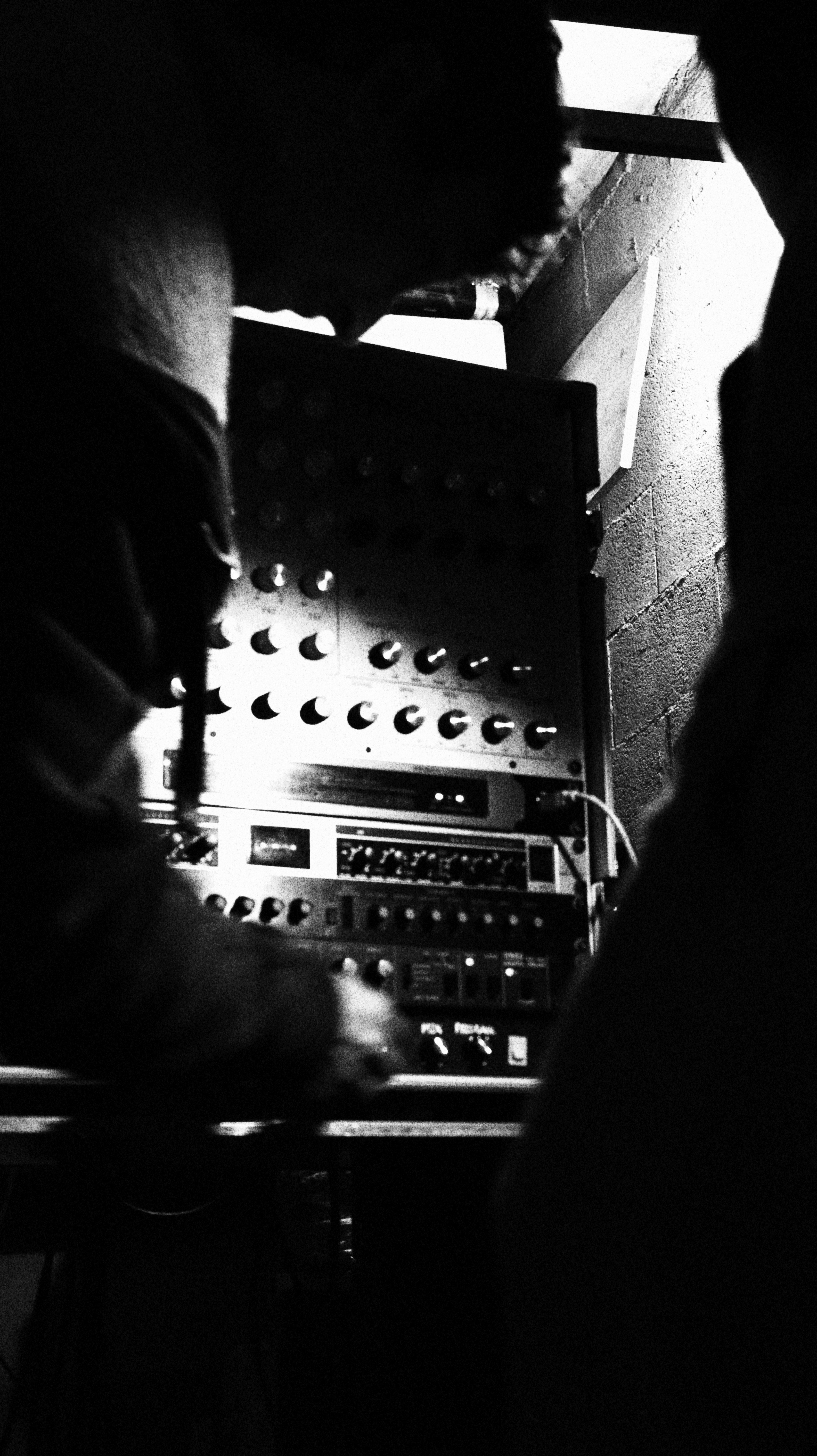Close-up black and white photo of a hand adjusting knobs on a custom Craftronics preamp for Val, during testing