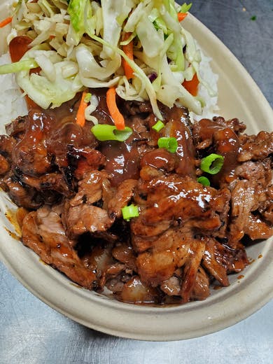 Thinly sliced Hawaiian Grilled Beef topped with green onions, served with two scoops of rice and traditional sides in a bowl.