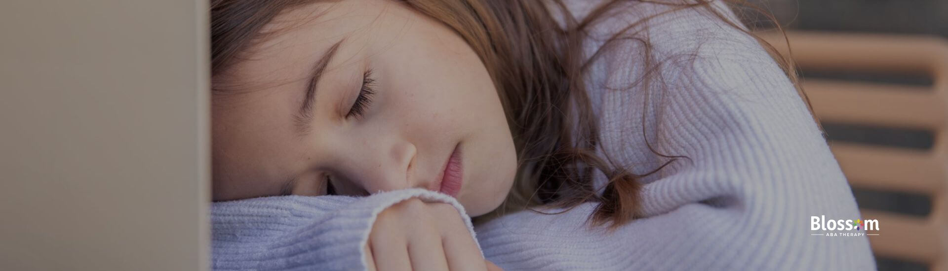 A tired child with brown hair sleeping with their head resting on a laptop during ABA therapy.