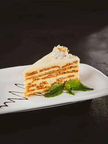 Slice of layered cake with cream filling on a white plate
