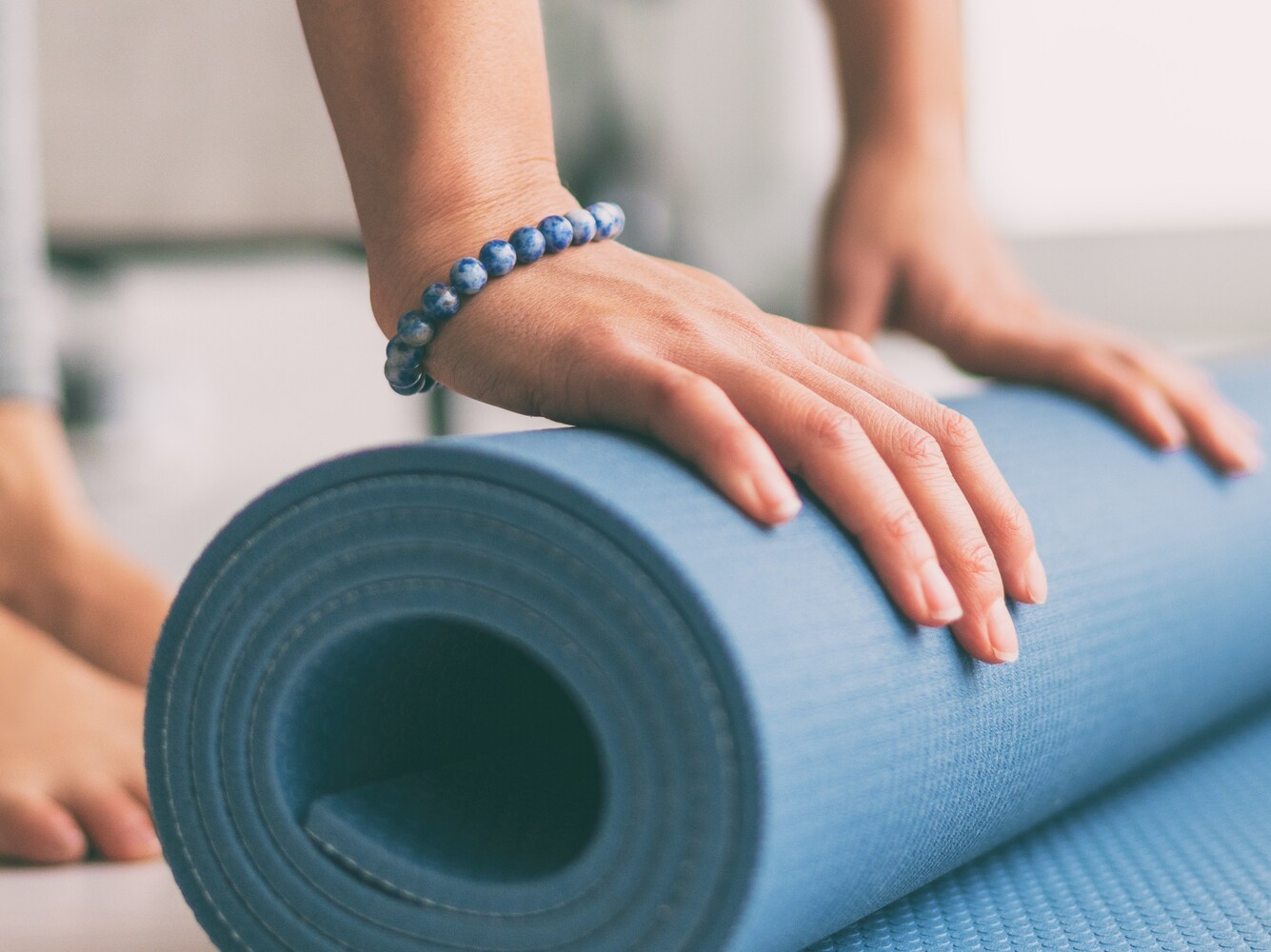 woman unrolling her exercise mat at the start of a pilates weight loss session
