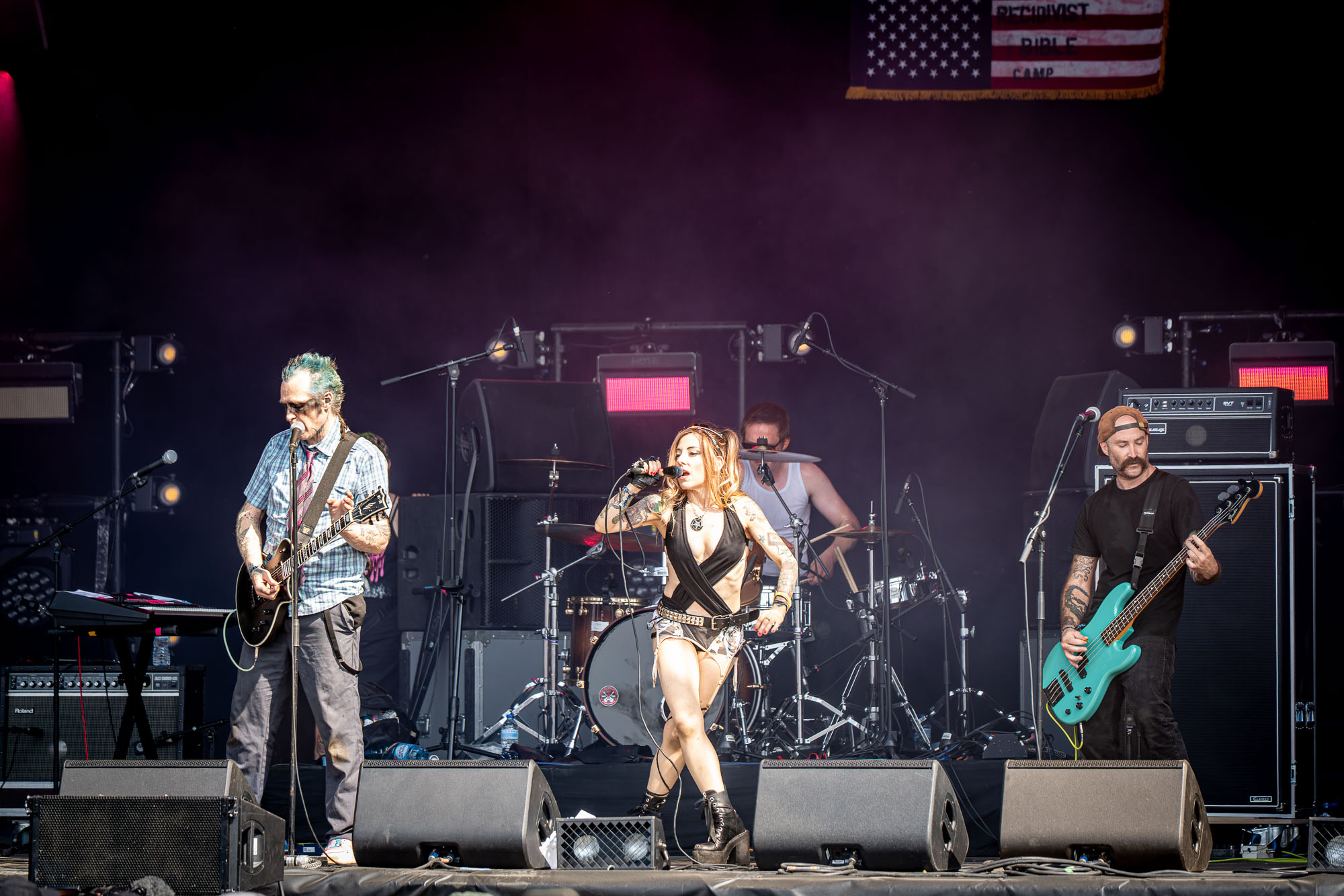 Groupe complet sur scène, chanteuse au centre devant un drapeau américain, Hellfest