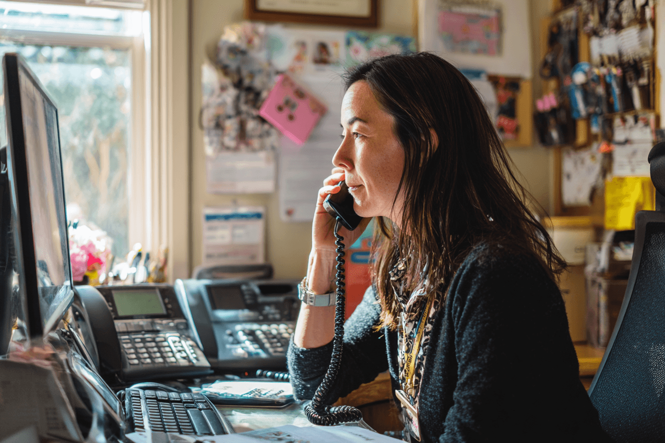 a home care agency owner, female in her 30s, in her home care agency office talking on the phone with a client
