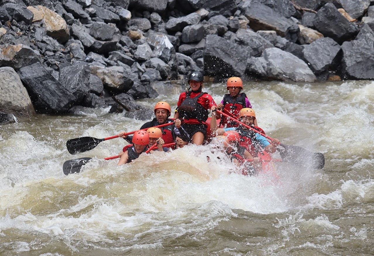 A group of rafters float in the river next to their inflatable