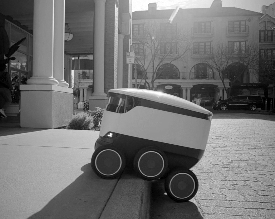 Black and white image of people working at a table with laptops, showing hands gesturing during discussion of digital content displayed on screens, with fabrica® logo in the corner.