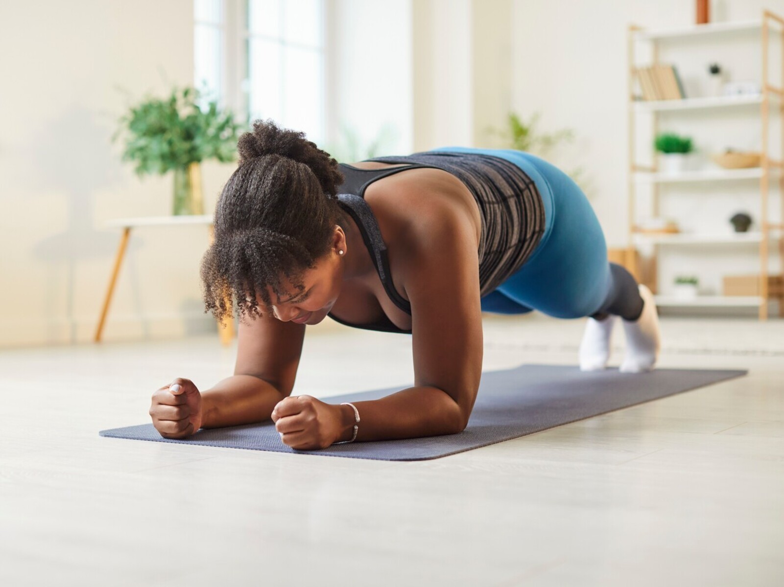 woman doing forearm planks for simple exercises to lose weight in her open-plan living room