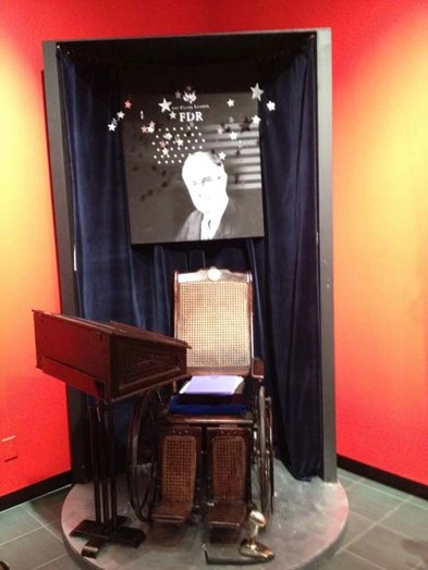 A wheel-chair with books on it and a stand near the wheel-chair