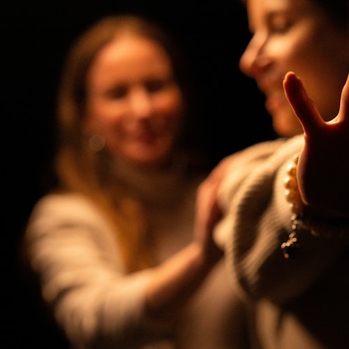 Two women walk carefully into the darkness.