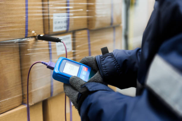 Image of a person checking the temperature of some palletised goods with a small devise 
