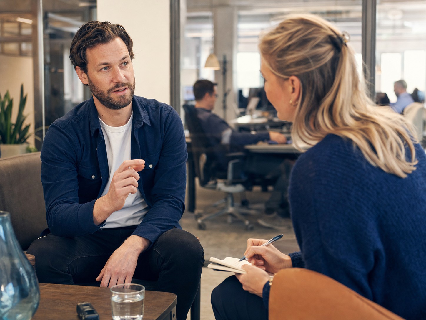 Een adviseur voert een persoonlijk strategiegesprek met een professional in een kantooromgeving.