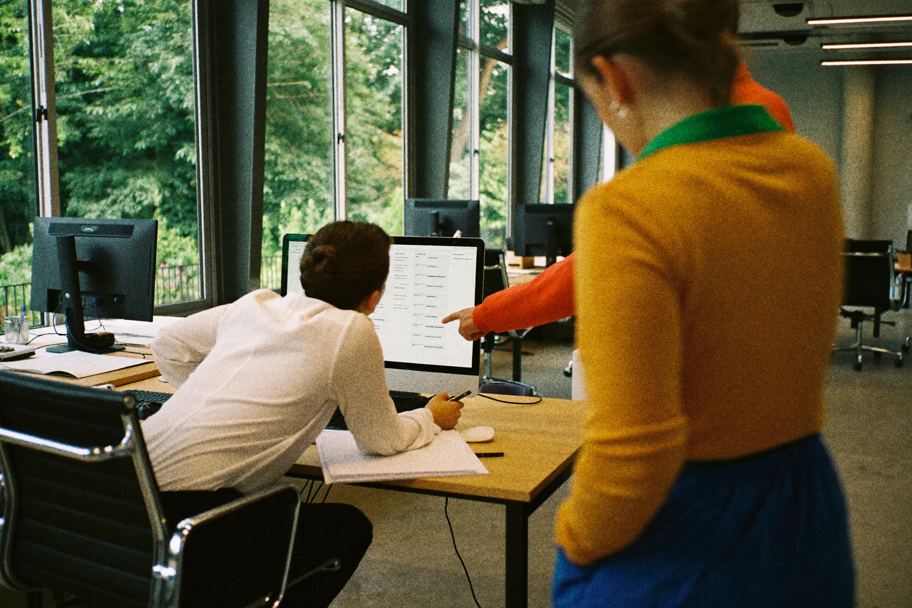 Een administratief medewerker controleert een weekplanning aan een bureau terwijl een collega meekijkt en wijst.