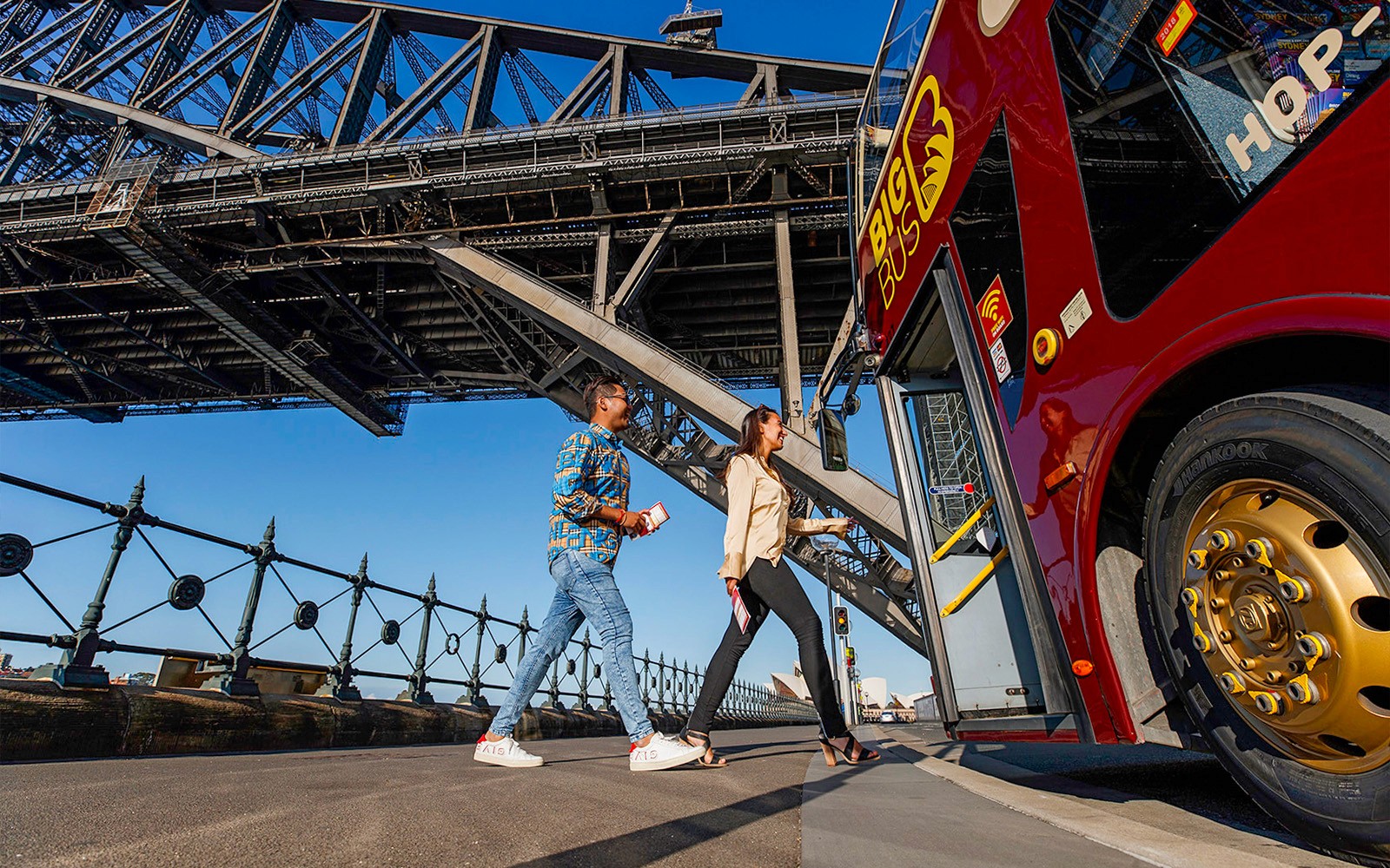Turistler, Sydney Limanı Köprüsü manzarası eşliğinde Dawes Point'te Big Bus Sydney'e biniyor.