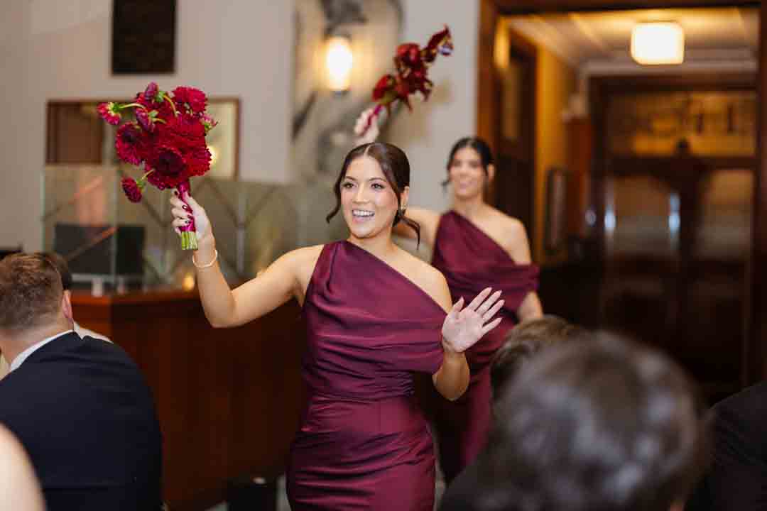 Bridesmaids in maroon dresses entering reception