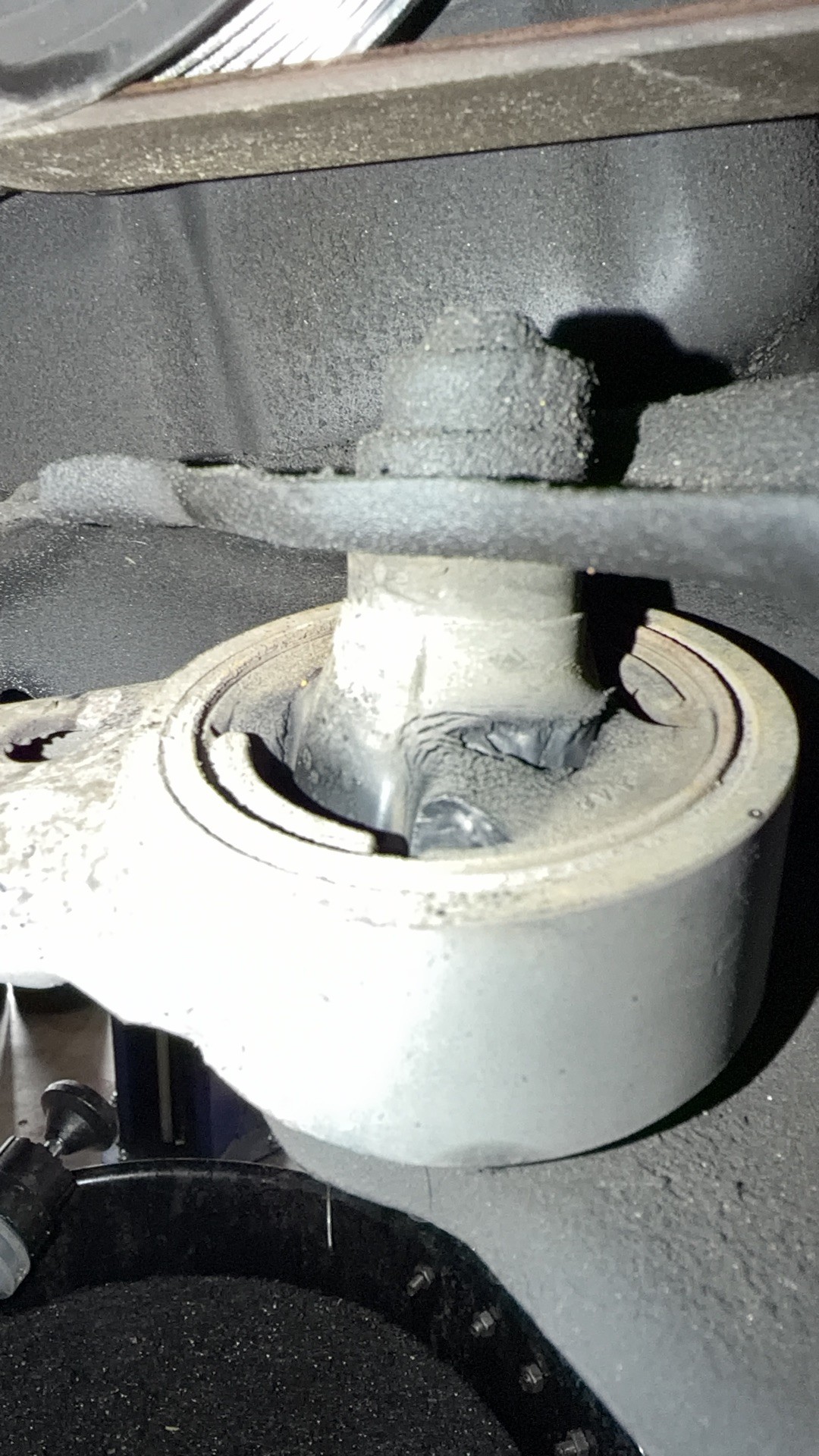 Second view of a worn front lower control arm bushing with a large gap in the rubber