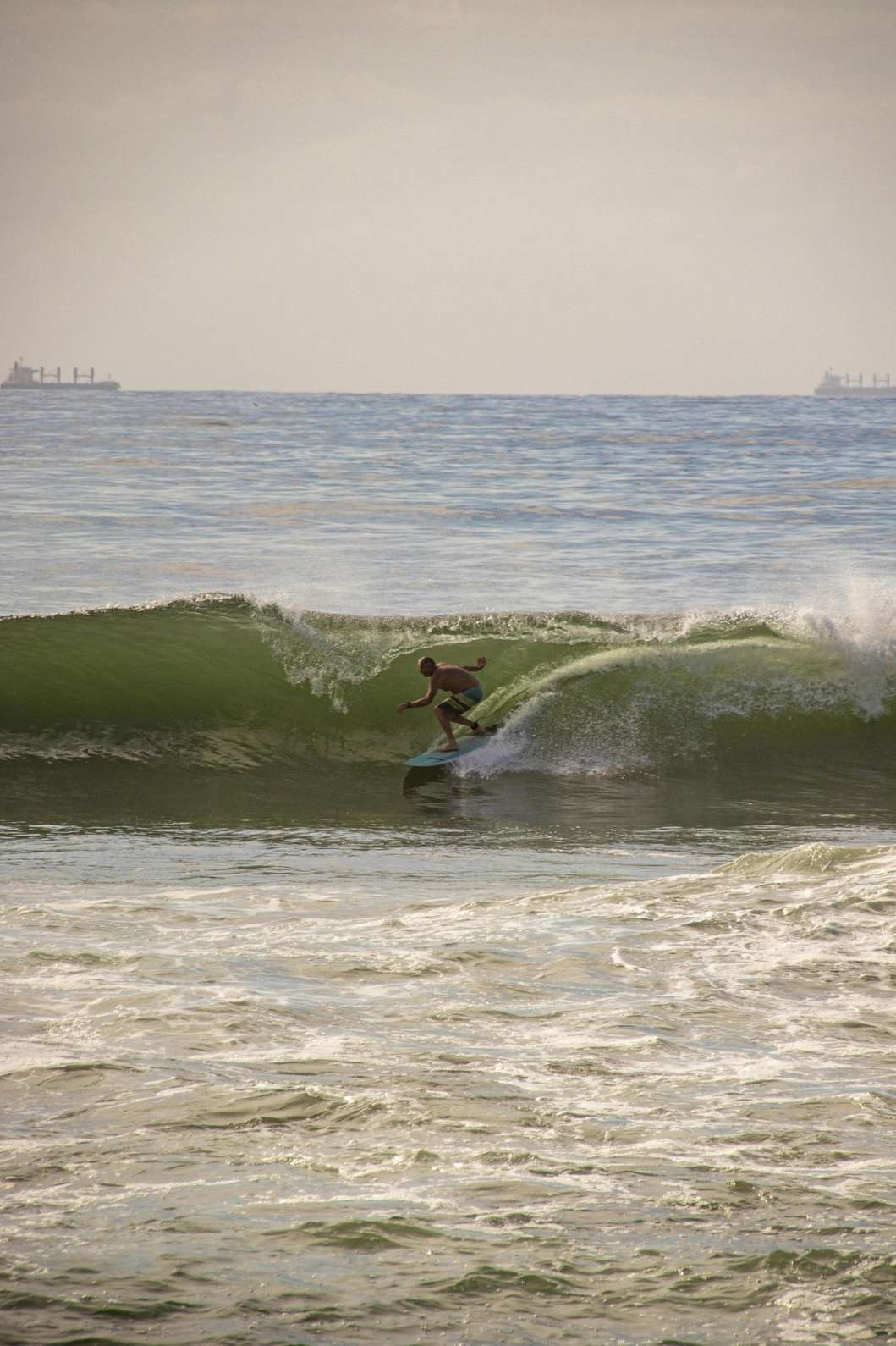 Long-distance shot of a surfer riding a powerful ocean break — surfboard rental in Africa