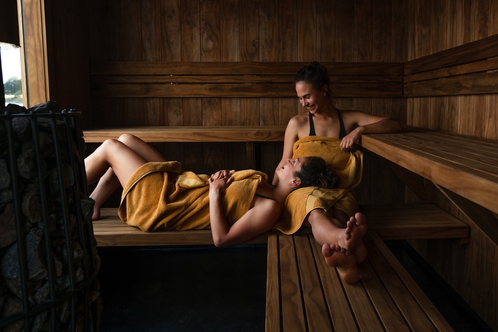 View through a wooden window shows a serene lake with gentle ripples and distant mountains shrouded in mist, creating a peaceful and inviting scene.