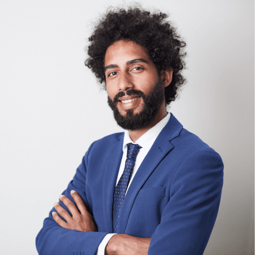 A young woman with long hair smiles while standing against a green backdrop, wearing a casual dark sweater.