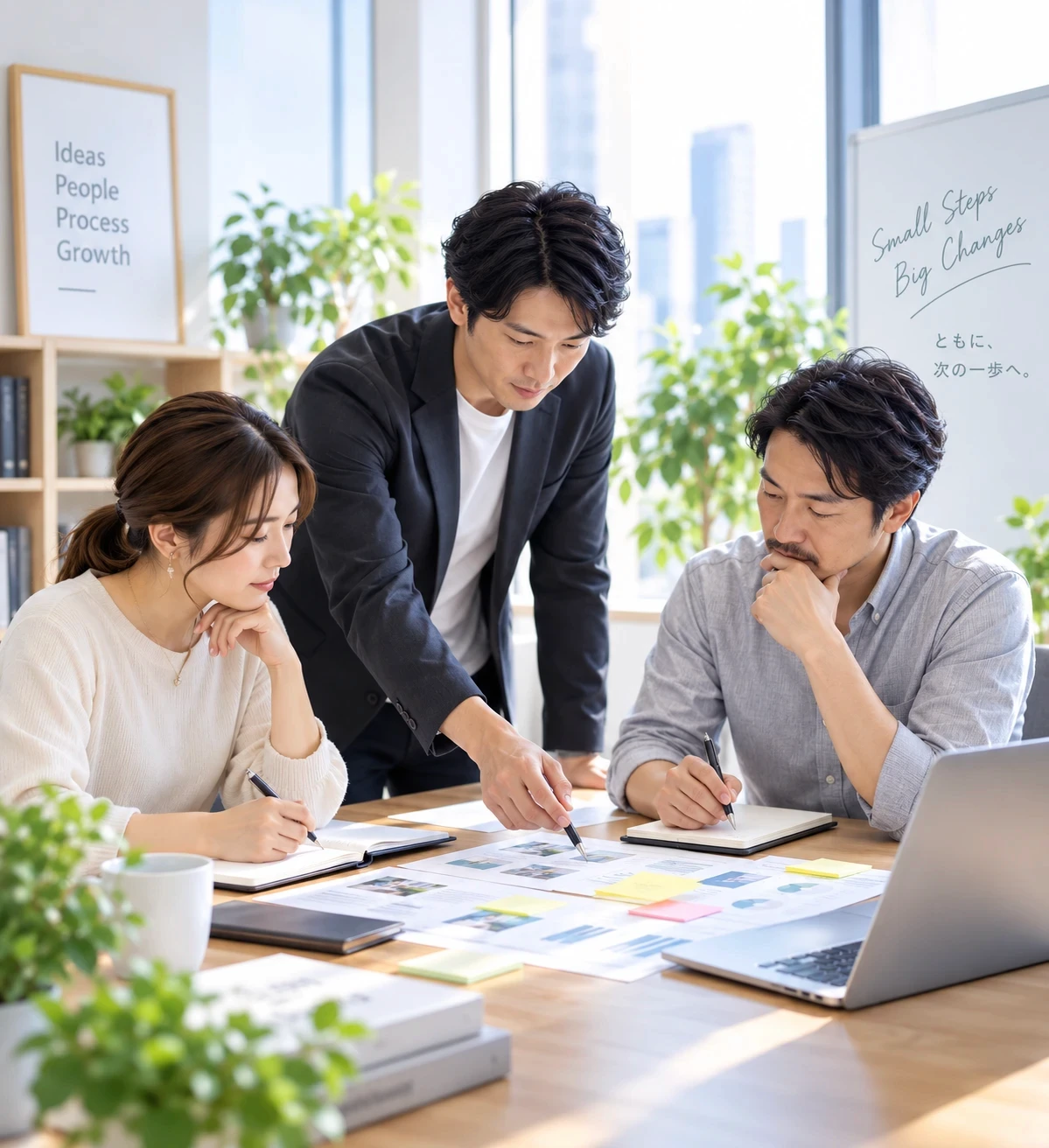 3名のスタッフが明るいオフィスで資料を囲み、業務について話し合う様子