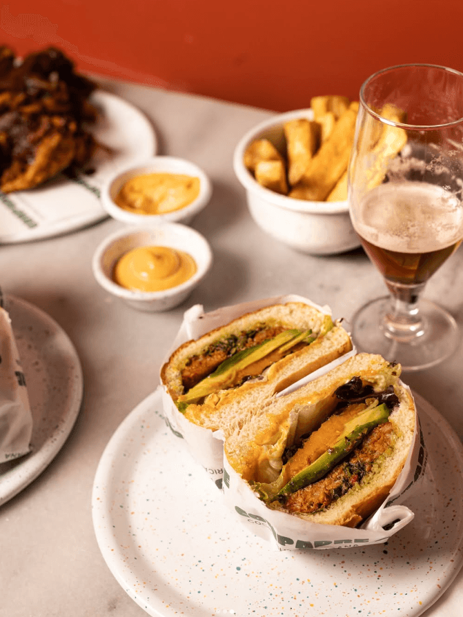 Burger latino façon street food avec avocat, fromage fondant et sauce maison, accompagné de frites et d’une bière artisanale au restaurant Compadre à Paris