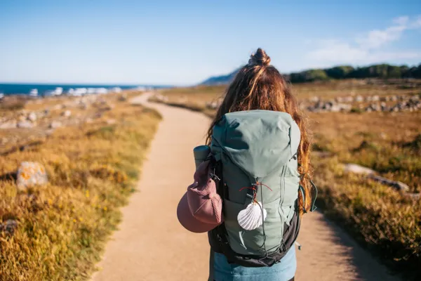 Peregrina com mochila num caminho costeiro — apoio Caminho da Costa · Táxi Afonso · 06 Caminha