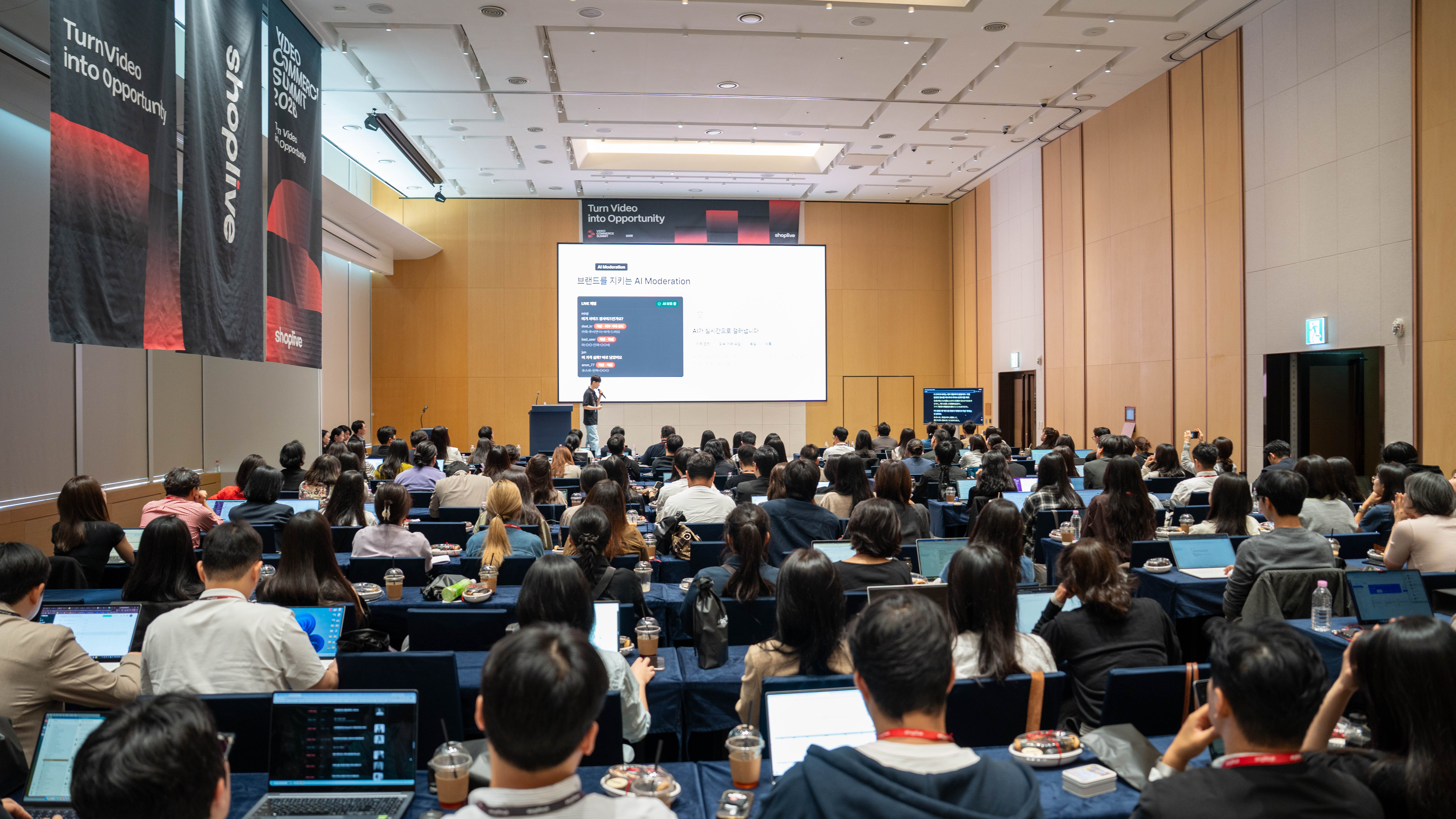 Video Commerce Summit 2026の会場となったロッテワールドタワーSKY31のセミナールームを参加者が埋め尽くした様子。ステージのスクリーンにはAIモデレーションの発表資料が映し出されている