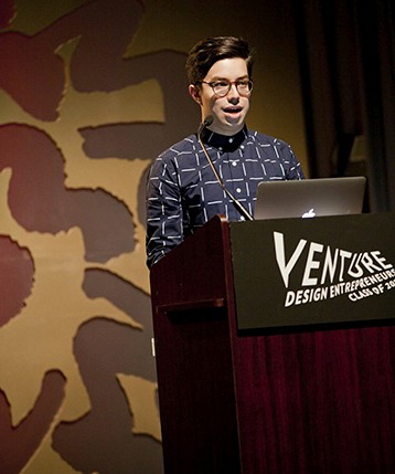 portrait of a young man with glasses giving a speech from the stand