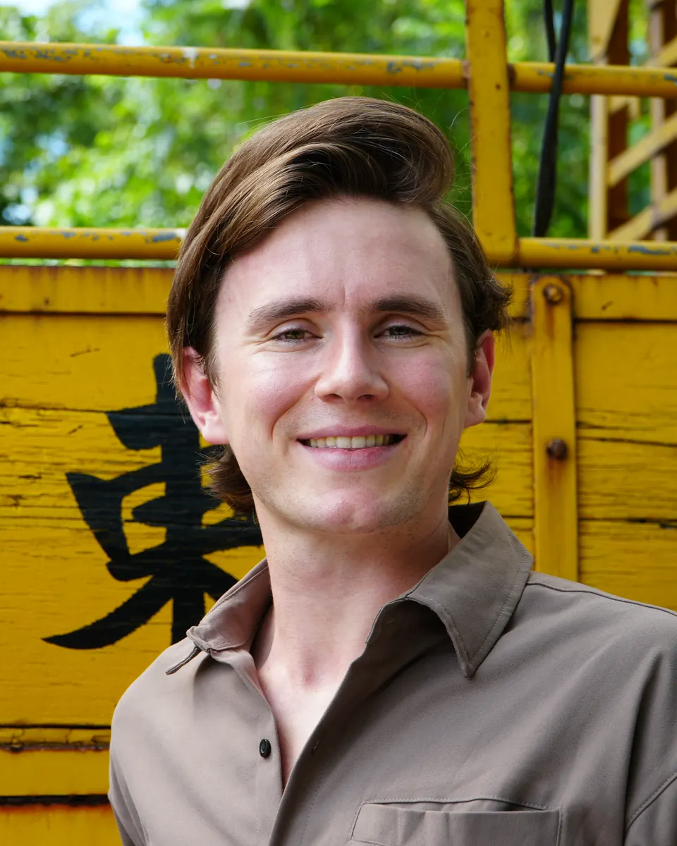 Jude Massey smiling in front of yellow wooden panels