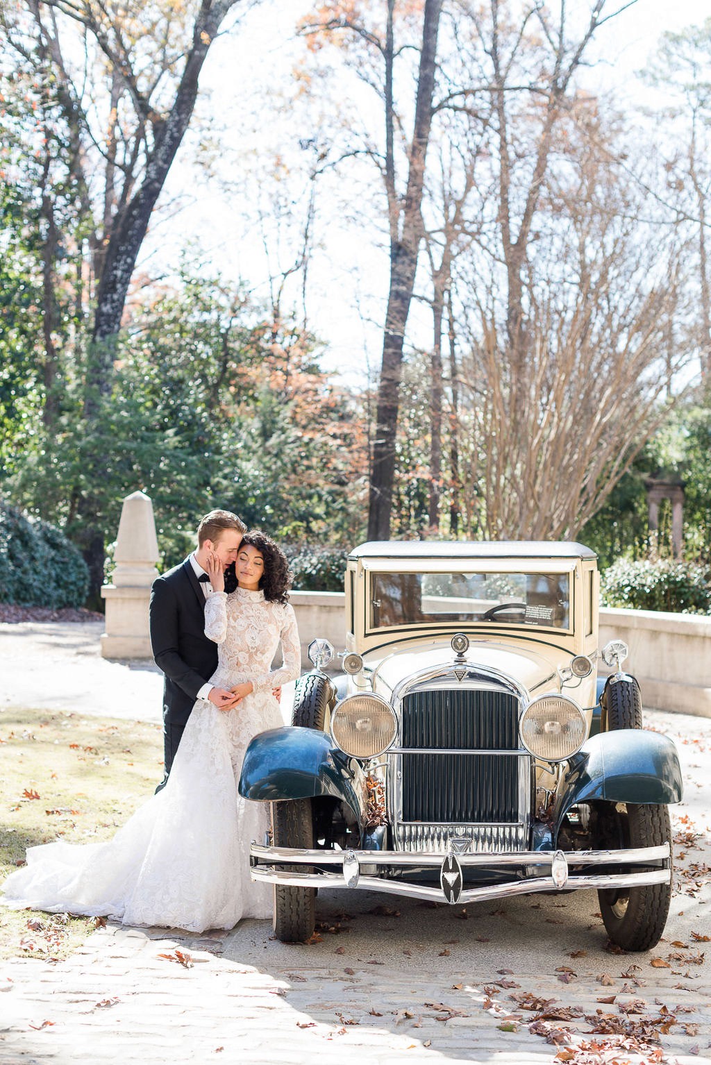 Wedding portrait of bride and groom next to vintage car at The Swan House in Atlanta, Georgia.