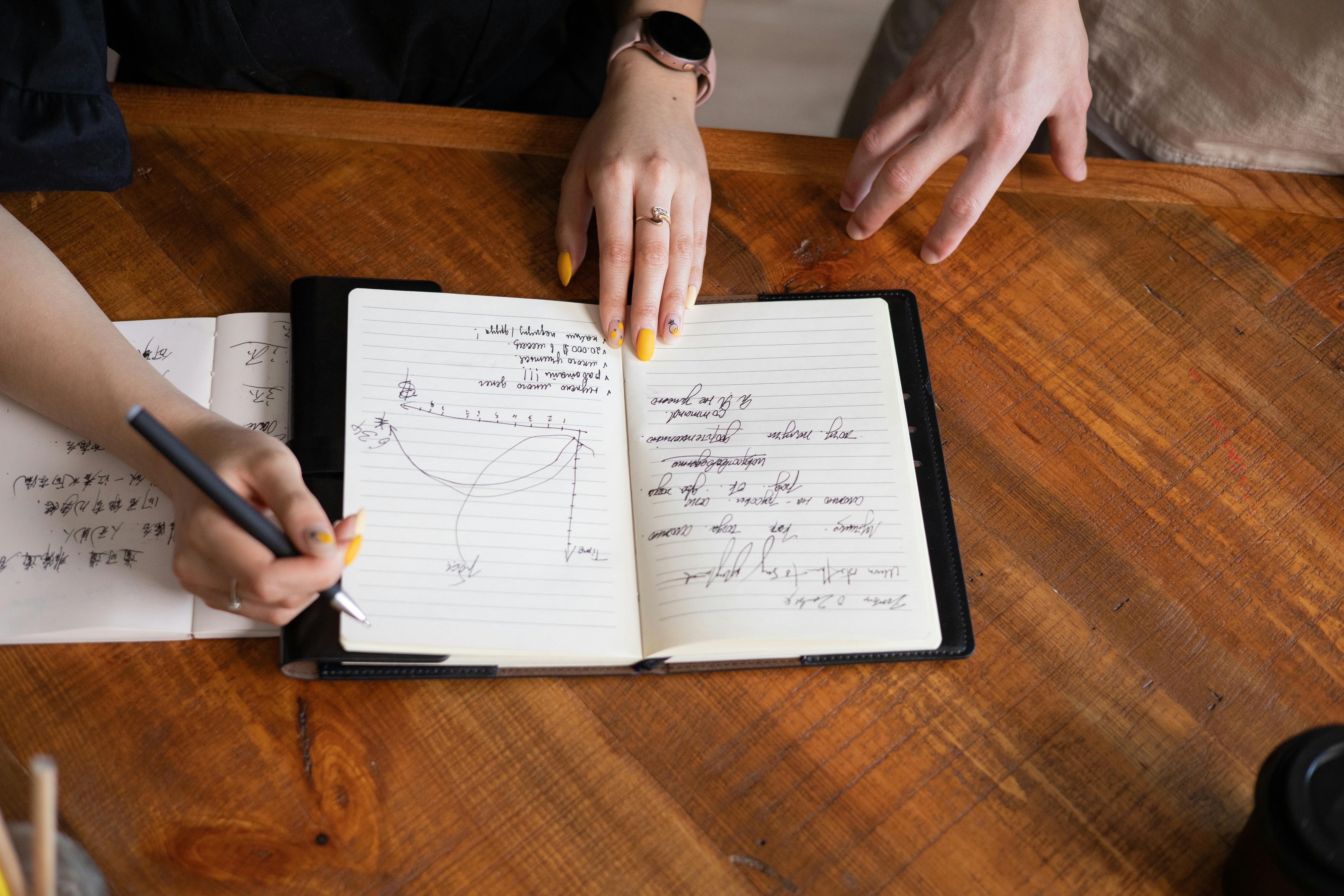 A close up image of a tacher doing lesson planning by writing in a notebook