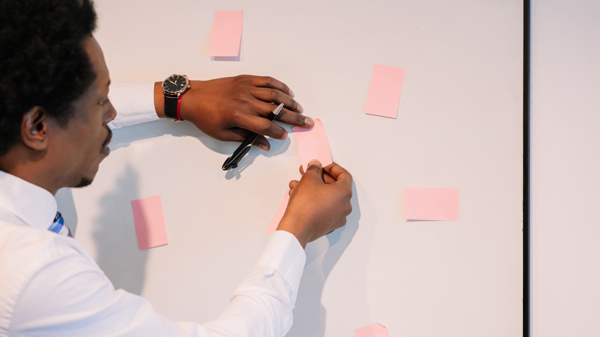 Business coach sticking a post-it note to a whiteboard during a strategy session