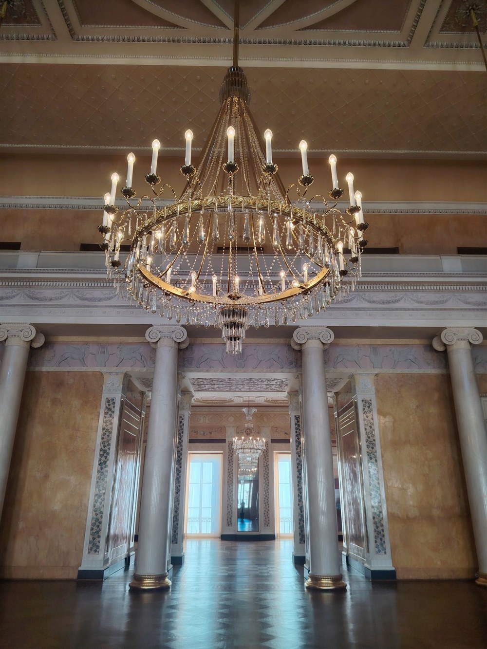 Festival hall of the Weimar City Palace with a large chandelier and columns