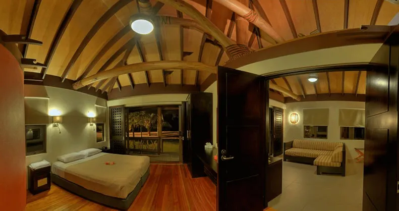 Spacious Uprising Beach Resort bure with a bedroom, separate lounge, and traditional vaulted wooden ceiling.