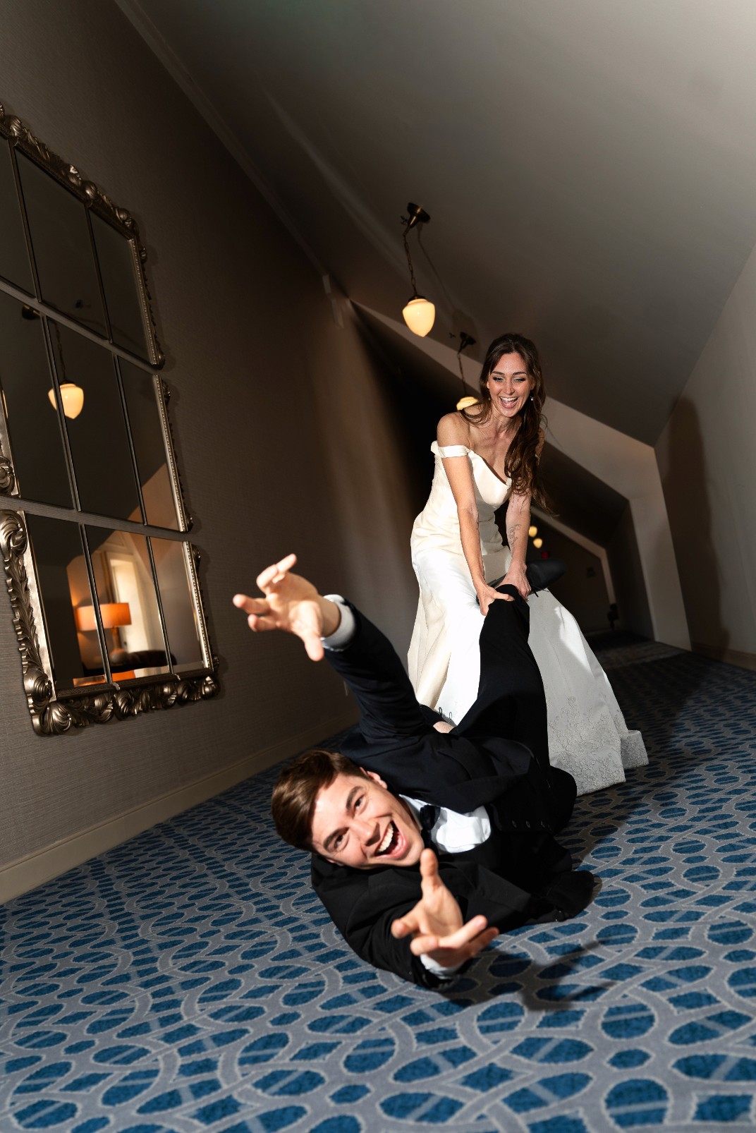 A bride in a white lace wedding dress holds a colorful bouquet of pink, yellow, and orange flowers.