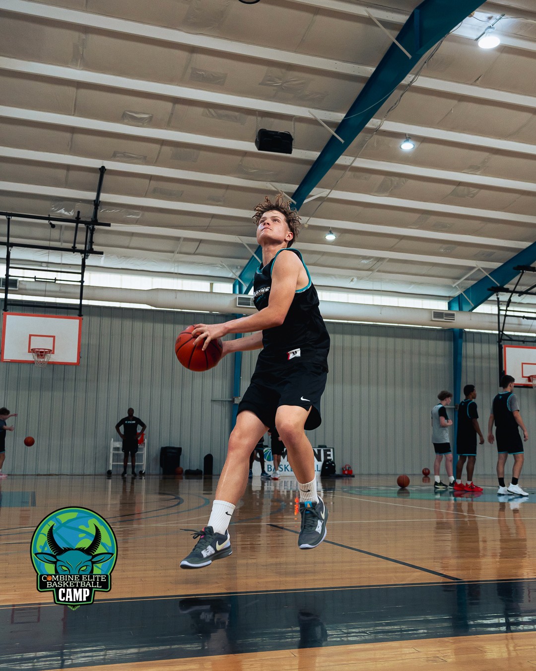 Jeune basketteur en pleine action de tir lors d’un camp d’entraînement en salle.