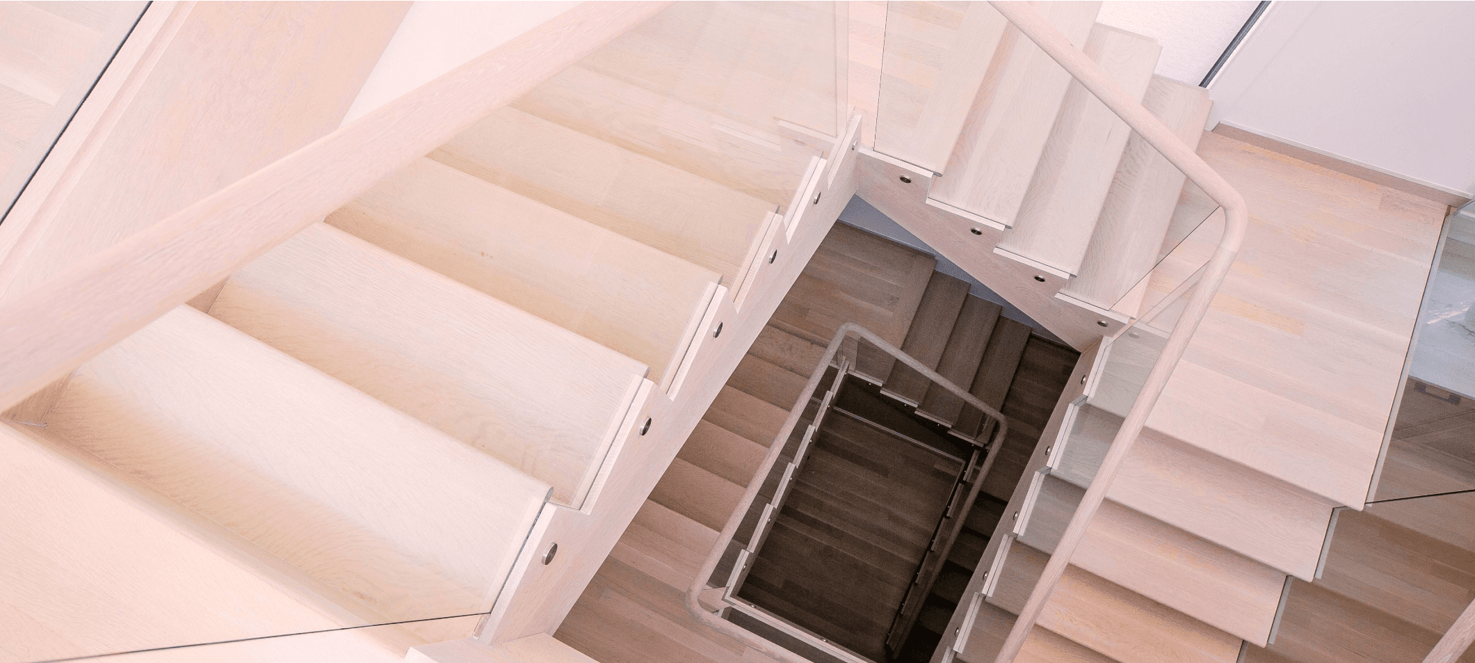 Looking down a white oak stair with square-edge treads and a frameless glass rail.