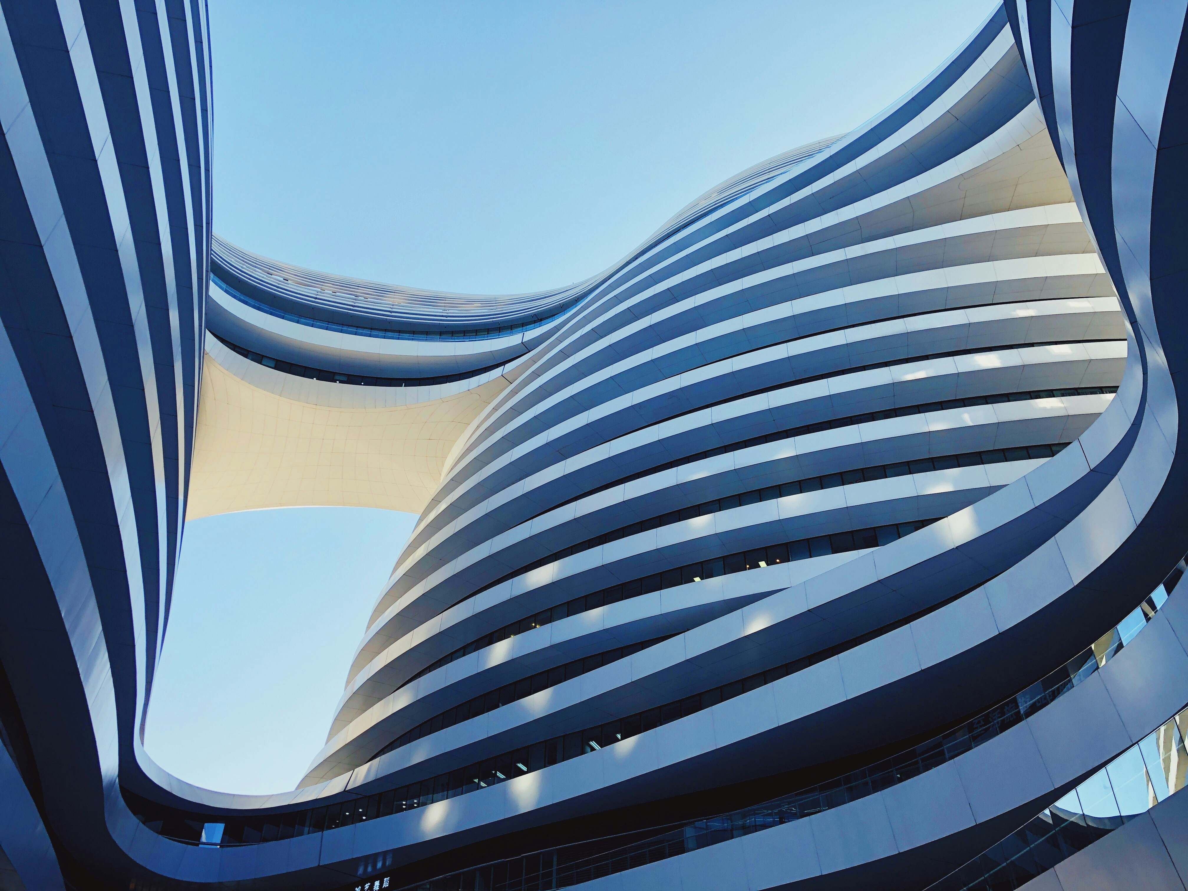 An abstract architectural image looking up at the curved shapes of a building
